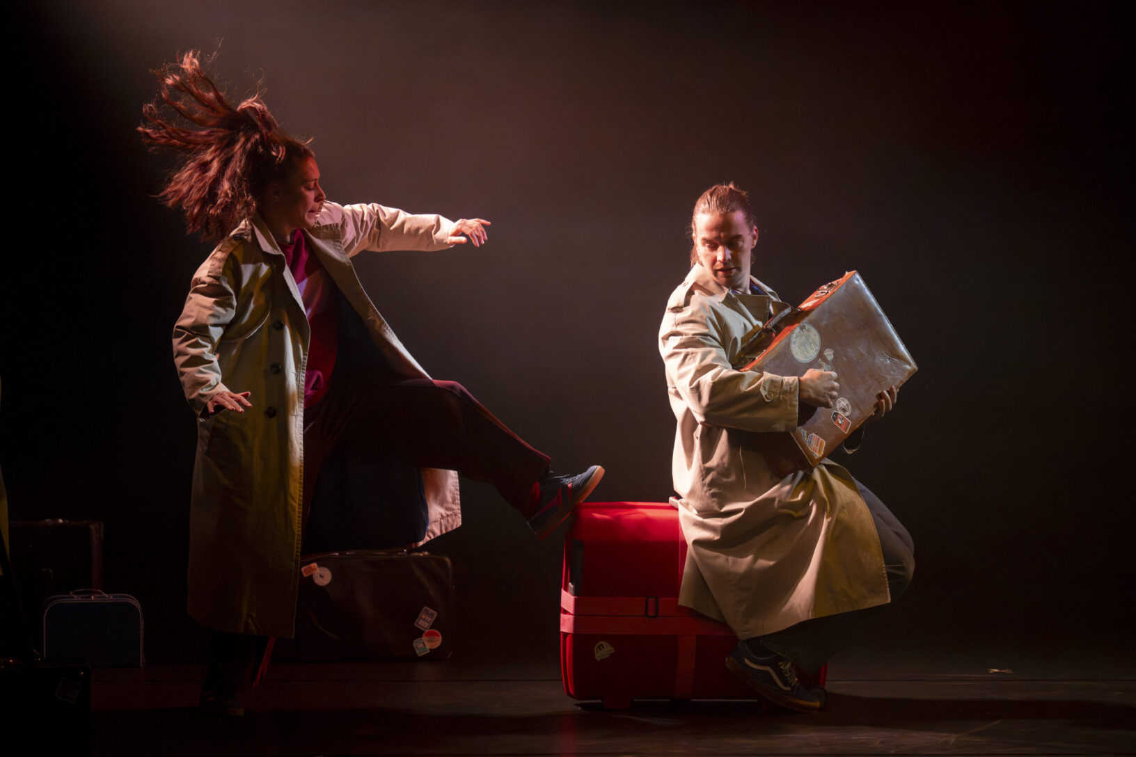 Irene K. - Zwei Darsteller in Trenchcoats heizen dem Publikum mit dynamischem Tanztheater ein: Der eine tritt mit wehenden Haaren aus, während der andere, ausdrucksstark und gelassen, auf einem Koffer sitzt – Tanz für junges Publikum voller Energie und Ausdruckskraft.